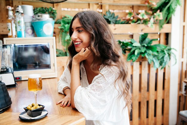 Mujer sonriente con aceitunas y cerveza