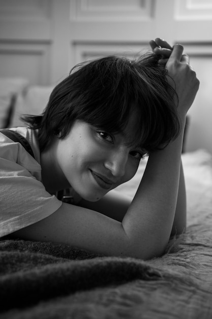 Mujer sonriente acostada en la cama autenticidad en blanco y negro