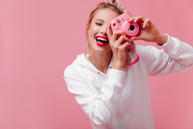 Mujer sonriente adorablemente con cabello rubio sosteniendo frente