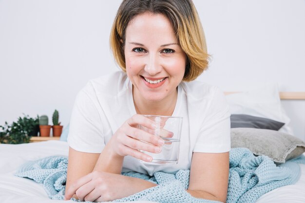 Mujer sonriente con agua en la cama