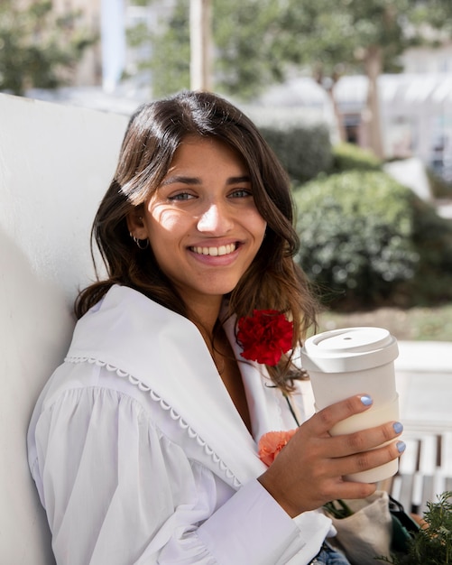 Foto gratuita mujer sonriente al aire libre con flores y taza de café