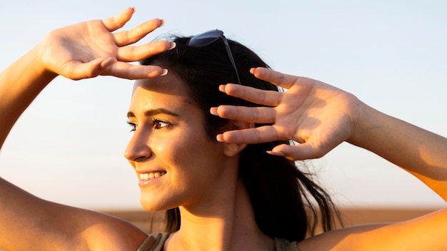 Mujer sonriente al aire libre bajo el sol que cubre su rostro