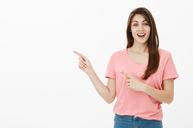 Mujer sonriente alegre apuntando hacia la esquina superior izquierda