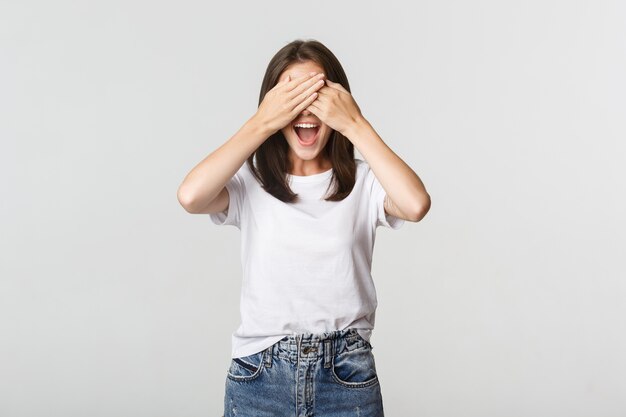 La mujer sonriente alegre cierra los ojos y espera sorpresa.