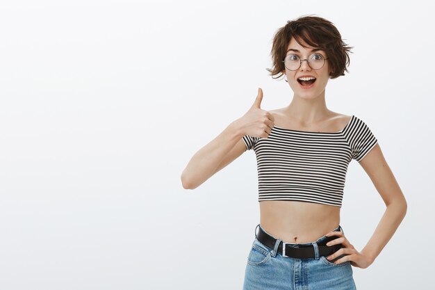 Mujer sonriente alegre que muestra el pulgar hacia arriba en señal de aprobación, me gusta y está de acuerdo, recomienda el servicio o producto de la empresa