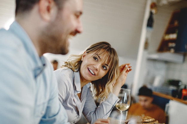 Mujer sonriente almorzando con su esposo y hablando con él en la mesa del comedor