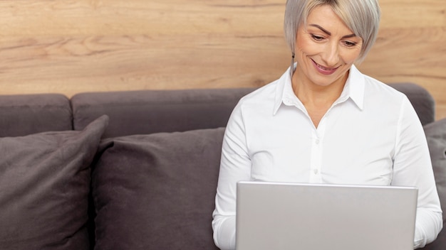 Mujer sonriente de alto ángulo que trabaja en la computadora portátil