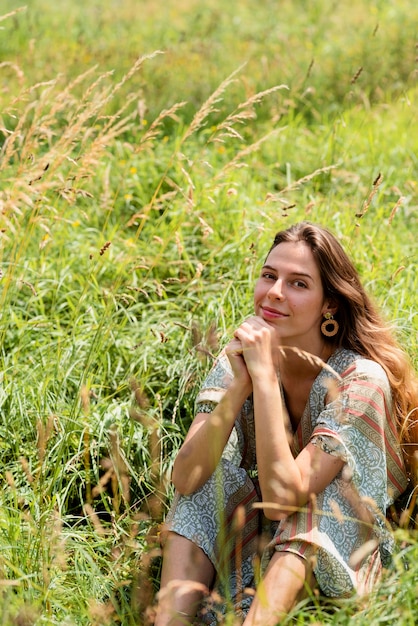 Mujer sonriente de alto ángulo sentada sobre el césped