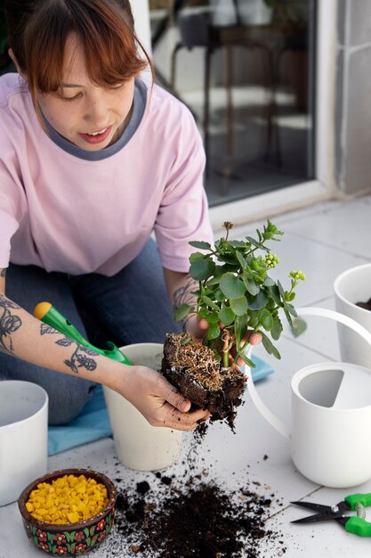 Mujer sonriente de alto ángulo trasplantando plantas