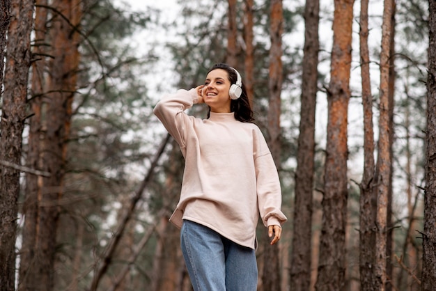 Mujer sonriente de ángulo bajo con auriculares