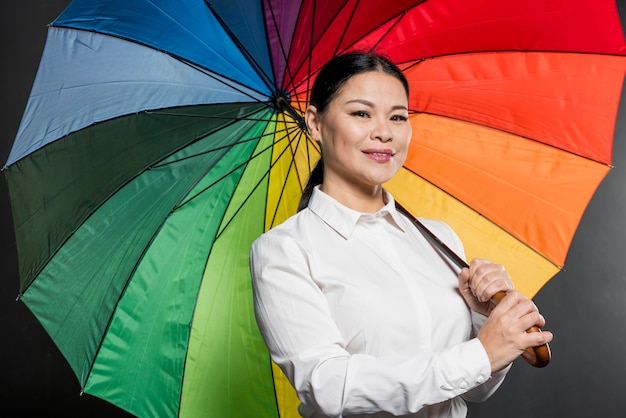 Mujer sonriente de ángulo bajo con coloridos paraguas