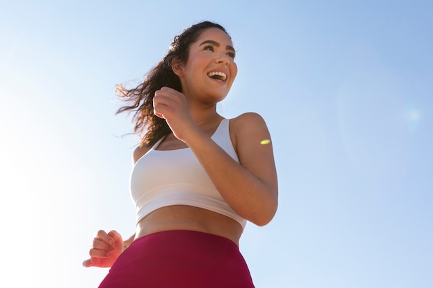 Mujer sonriente de ángulo bajo corriendo