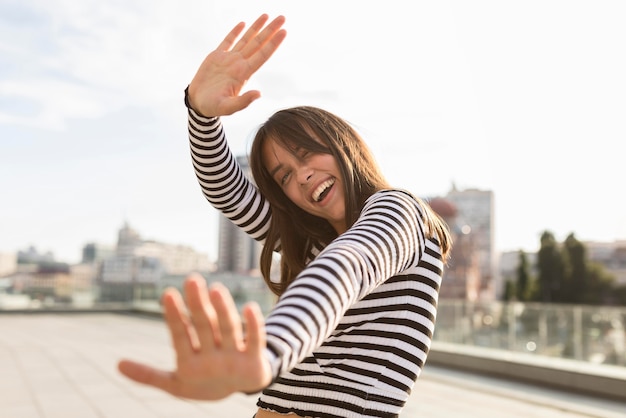 Mujer sonriente de ángulo bajo divirtiéndose mientras posa