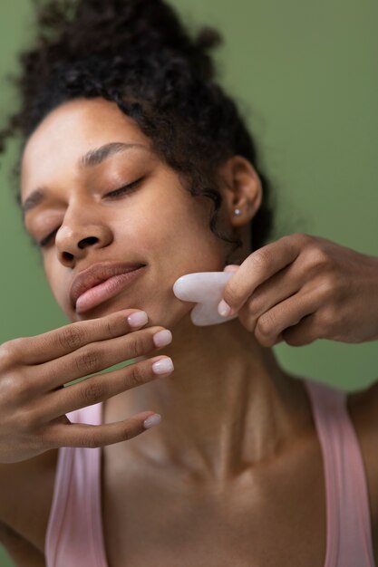 Mujer sonriente con ángulo bajo gua sha