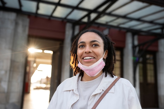 Mujer sonriente con ángulo bajo de máscara rosa