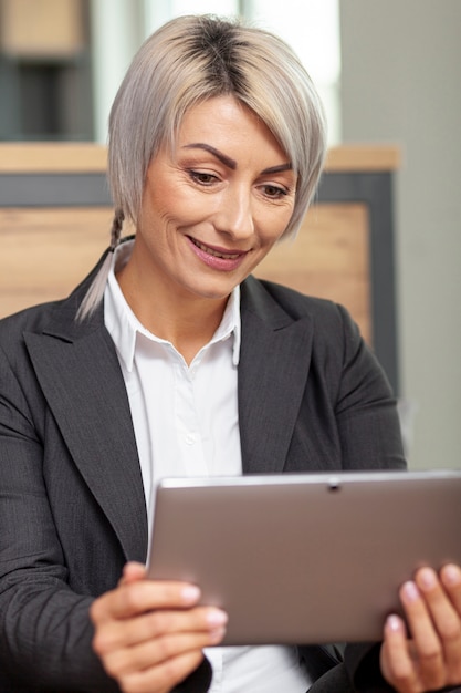 Foto gratuita mujer sonriente de ángulo bajo en tableta