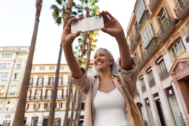 Mujer sonriente de ángulo bajo tomando selfie