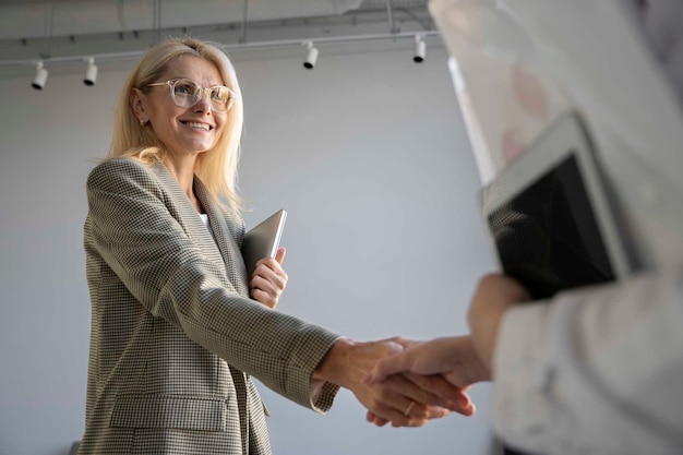 Foto gratuita mujer sonriente de ángulo bajo en el trabajo