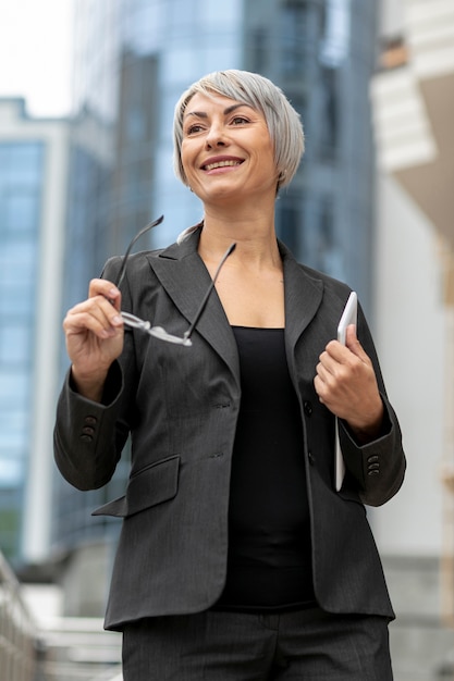 Foto gratuita mujer sonriente de ángulo bajo con traje