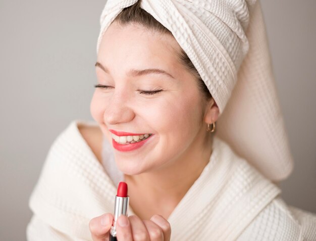 Mujer sonriente aplicando lápiz labial