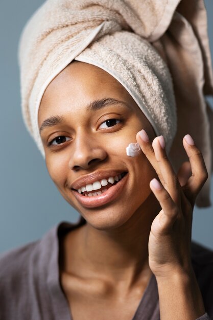 Mujer sonriente aplicando vista lateral de crema facial