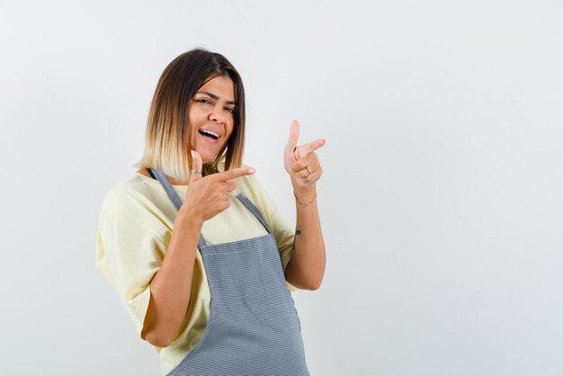 La mujer sonriente apunta a la derecha con los dedos índices sobre fondo blanco.