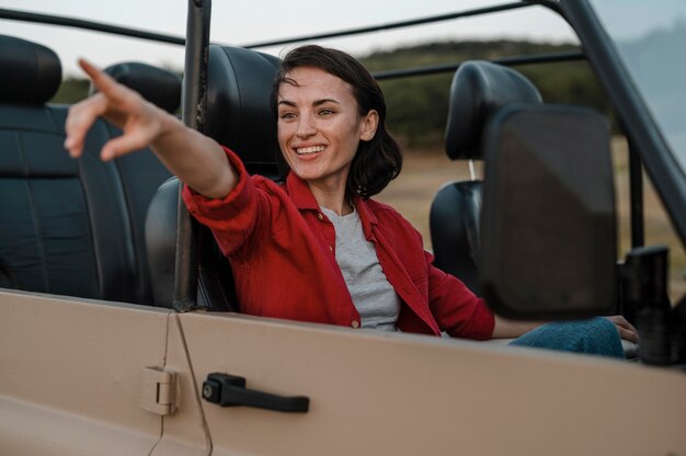Mujer sonriente apuntando mientras viaja solo en coche