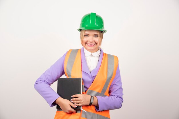 Mujer sonriente del arquitecto en la tableta de la explotación agrícola del casco en blanco.