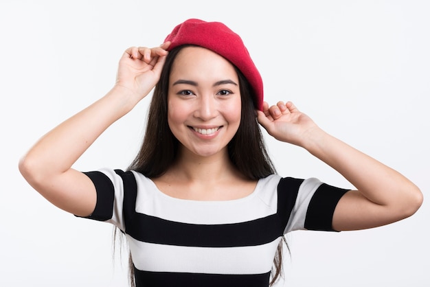 Mujer sonriente arreglando su sombrero