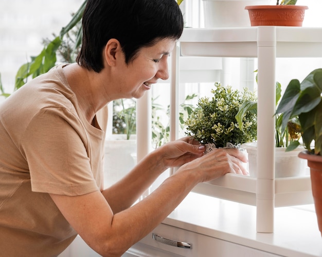 Mujer sonriente arreglando sus plantas de interior