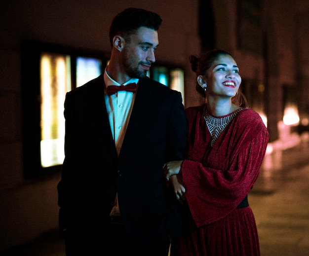 Mujer sonriente atractiva encantadora que camina con el hombre joven en la calle