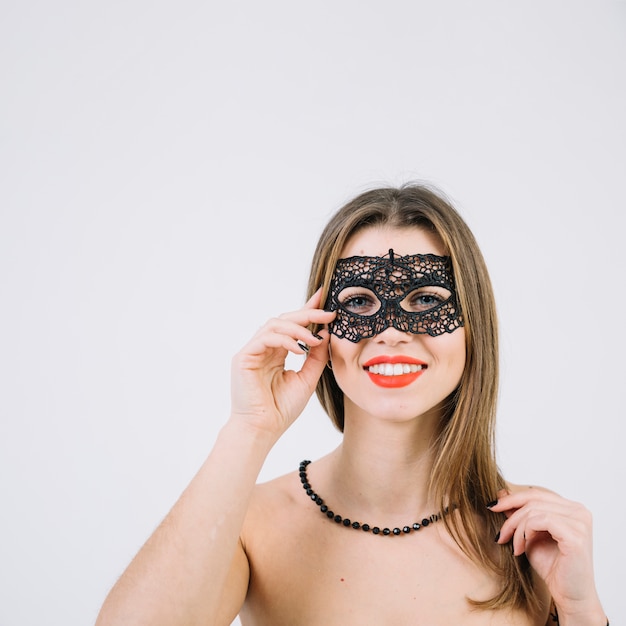 Mujer sonriente atractiva en máscara del carnaval de la mascarada en el fondo blanco