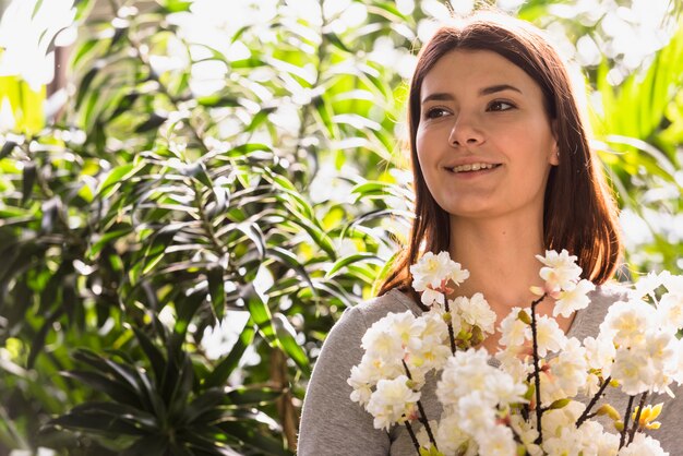 Mujer sonriente atractiva que sostiene el manojo de ramitas de la flor