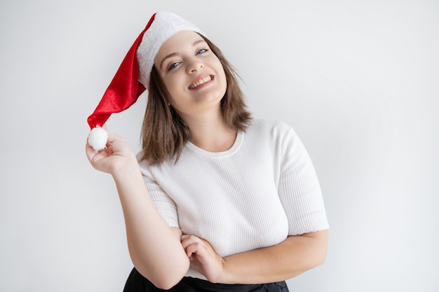 Mujer sonriente atractiva en el sombrero de papá noel que liga en la cámara