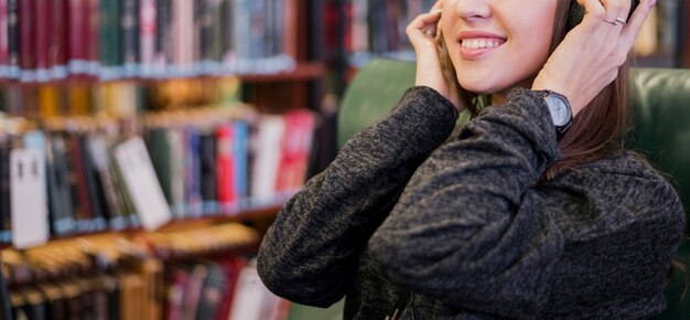 Mujer sonriente con auriculares cerca de estantería