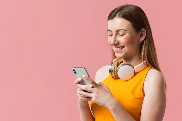 Mujer sonriente con auriculares comprobando el móvil