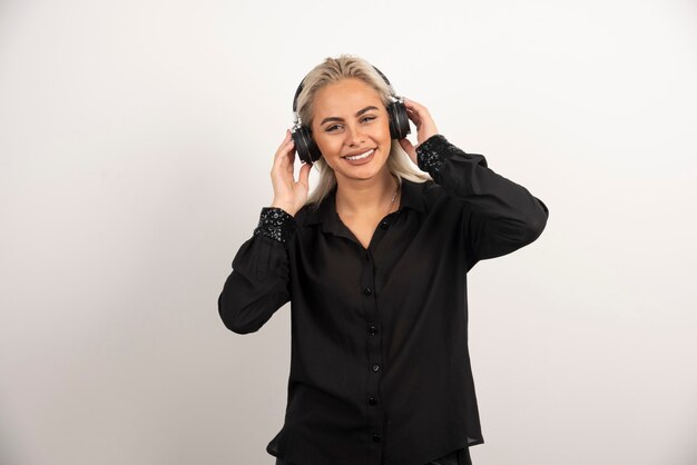 Mujer sonriente con auriculares de pie sobre fondo blanco. Foto de alta calidad