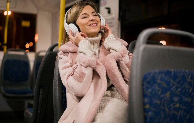 Mujer sonriente con auriculares sentado en el autobús