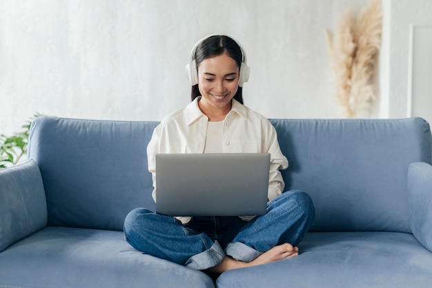 Mujer sonriente con auriculares trabajando en equipo portátil