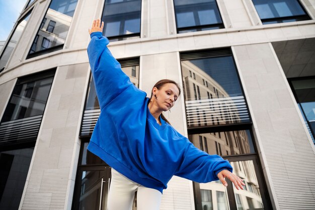 Mujer sonriente bailando al aire libre en ángulo bajo