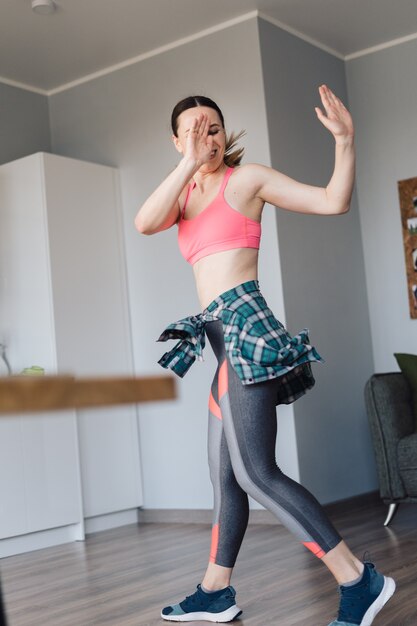 Mujer sonriente bailando en medio de la sala de estar disfrutando de ella y la vida