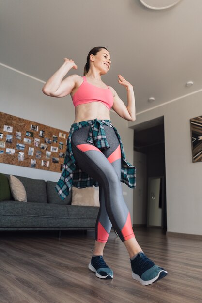 Mujer sonriente bailando en medio de la sala de estar disfrutando de ella y la vida