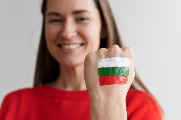 Mujer sonriente con bandera búlgara pintada en su mano