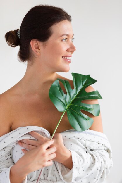 Mujer sonriente en bata de baño con hoja