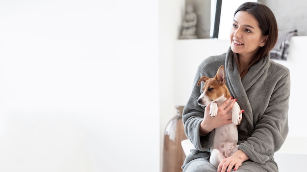 Mujer sonriente en bata de baño con su perro