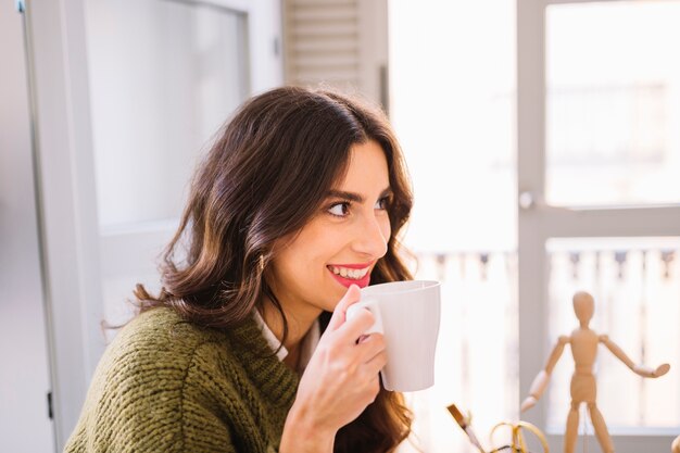 Mujer sonriente bebiendo bebida caliente