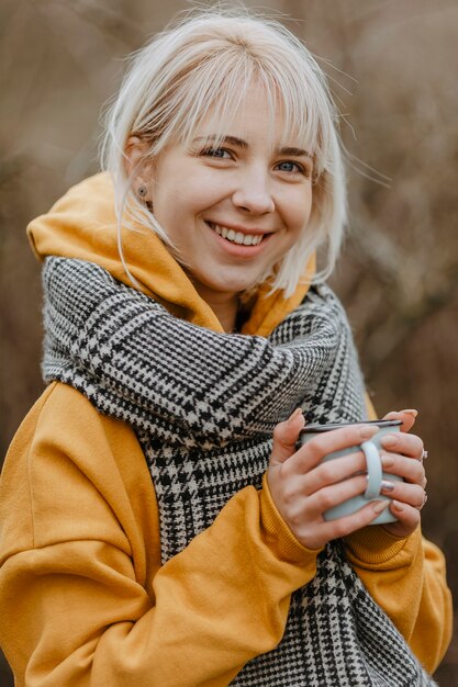 Mujer sonriente bebiendo té para calentar