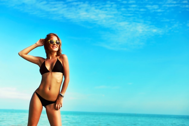 Mujer sonriente en bikini disfrutando del cielo azul