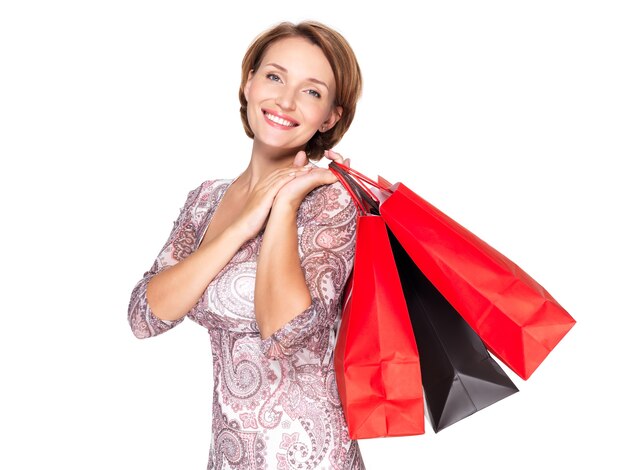 Mujer sonriente con bolsas de compras sobre pared blanca
