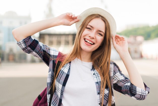 Mujer sonriente bonita que sostiene el sombrero y la presentación